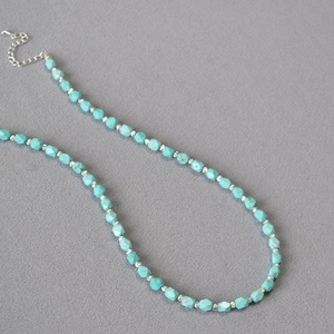 Macro view of faceted turquoise beads and silver metal spacers on a handmade necklace