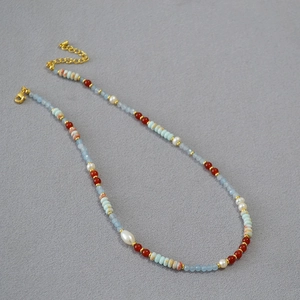 Retro beaded necklace with blue stone, red agate, and baroque pearl on dark background