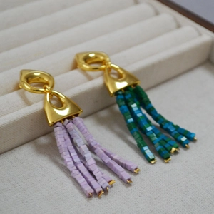 Detail of bohemian tassel earrings with gold geometric top and green bead fringe