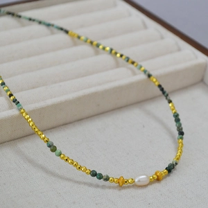 Detail of beaded necklace with African turquoise, gold spacers and a freshwater pearl