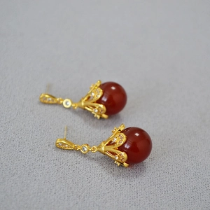 Detail of vintage gold flower earrings with red agate beads and sparkling zircon stones