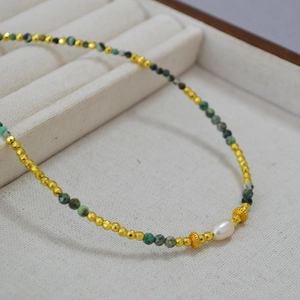 Close-up of African turquoise beads and freshwater pearl with golden crown spacers