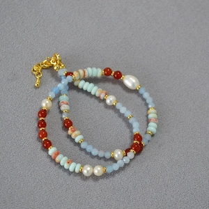 Detail of beaded necklace with freshwater pearls, red agate, and blue amazonite stones