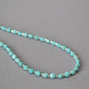Macro shot of turquoise beaded necklace featuring faceted cut stones and silver metal spacers