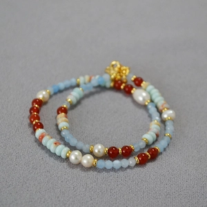 Detail of beaded necklace with blue stones, red agate, pearls and golden spacers