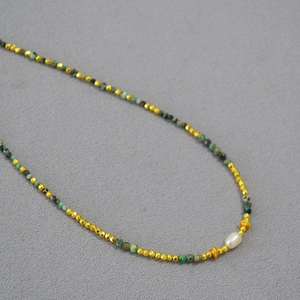 Detail view of African turquoise and freshwater pearl beaded necklace with gold spacer beads