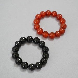 Détail des bracelets élastiques en perles d'agate noires et rouges de 14mm sur tissu