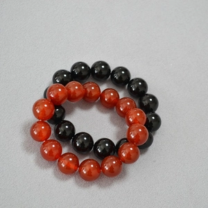 Détail de bracelets extensibles en agate rouge et noire de 14mm au fini poli brillant