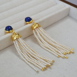 Lapis lazuli tassel earrings with long white pearl strands on elegant jewelry tray