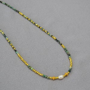 Macro detail of natural turquoise beads and freshwater pearl with golden faceted spacers