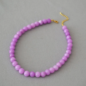Retro purple apatite bead necklace with golden lobster clasp on a grey background