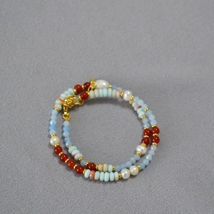 Macro detail of beaded necklace with blue stones, red agate, and freshwater pearls