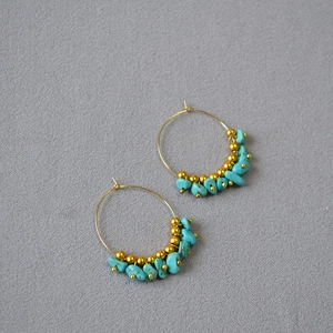 Detail view of boho gold hoop earrings with irregular turquoise beads and golden accents