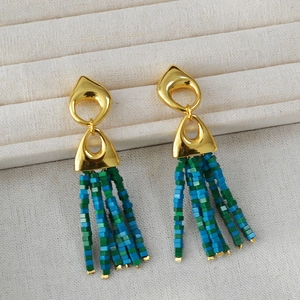 Macro detail of bohemian fringe earrings with gold geometry and blue green beads