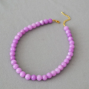 Detail view of purple stone beaded necklace with golden lobster clasp and chain