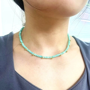 Collier ras de cou en perles d'amazonite et métal doré porté par un mannequin en lumière