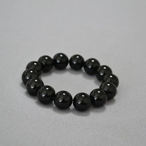 Vue détaillée du bracelet élastique en perles d'onyx noir de 14mm avec fini poli brillant