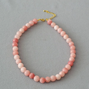 Macro detail of natural pink apatite round beads necklace with gold lobster clasp