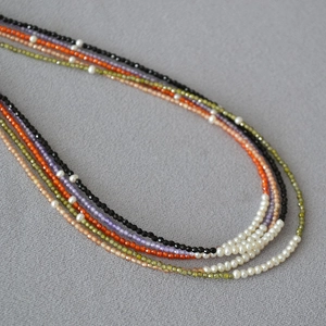 Detailed macro view of stacked colorful gemstone beaded necklaces with small pearls