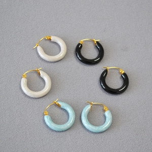 Detail of three pairs of pearlescent enamel hoop earrings in white, black and light blue