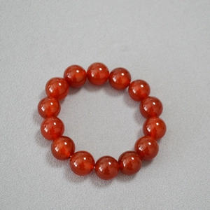 Vue de dessus de perles d'agate rouge 14mm sur bracelet élastique sur tissu gris