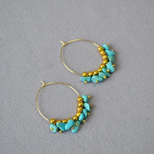 Detail of bohemian gold hoop earrings featuring turquoise stones and polished metal beads