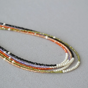 Detail of colorful multi-strand beaded necklace with small gemstones and white pearls