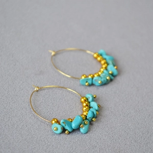 Close-up of gold hoop earrings featuring irregular turquoise beads and metallic spacers