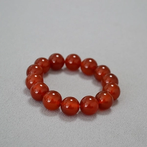 Gros plan sur des perles d'agate rouge de 14mm montrant une texture lisse et un bel éclat