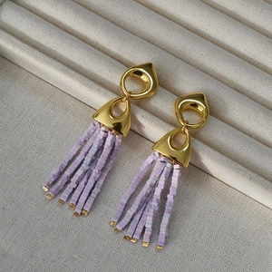 Detail of vintage gold geometric studs with cascading purple bead tassels on beige fabric