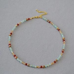 Détail d'un collier bohème avec perles bleues et marron et fermoir mousqueton doré