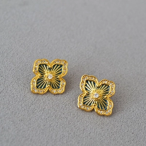 Macro detail of gold flower stud earrings with blue enamel and sparkling micro-diamonds