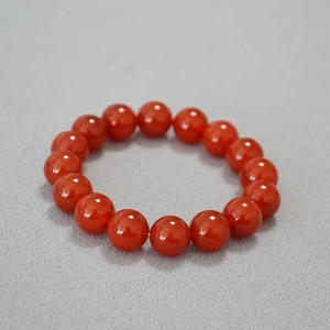 Gros plan d'un bracelet en perles d'agate rouge 14mm avec finition brillante sur tissu