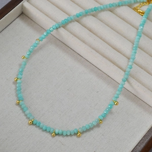 Collier en perles d'amazonite bleu ciel avec pendentifs dorés sur un présentoir