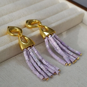 Detailed close-up of vintage gold geometric earrings with purple beaded square tassels
