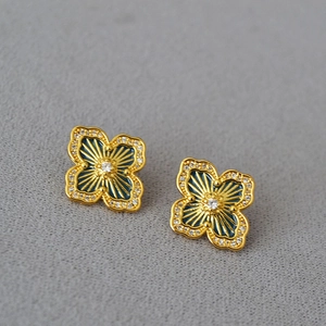 Detail of clover earring with blue enamel, golden rays, and white zircon inlay