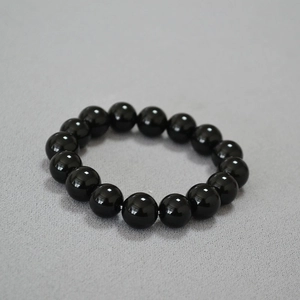 Gros plan de perles d'agate noire polies de 14mm sur un bracelet élastique brillant
