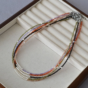Detail of multi-layered colorful beaded necklaces with freshwater pearls and lobster clasp