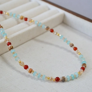 Collier de perles ethnique avec perles turquoises et rouges sur tissu blanc texturé