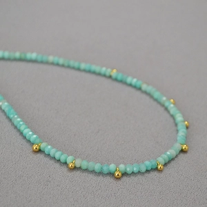 Gros plan d'un collier en amazonite avec perles facettées bleu-vert et détails dorés