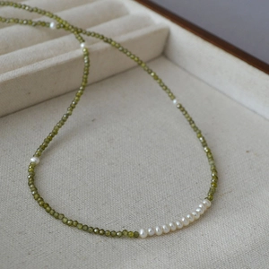 Elegant thin peridot beaded necklace with freshwater pearls in a beige jewelry box