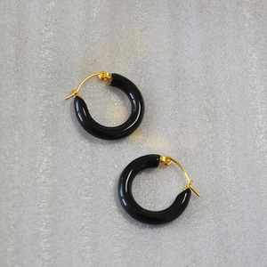 Close-up of black pearlescent enamel hoop earrings with gold metal clasp for women
