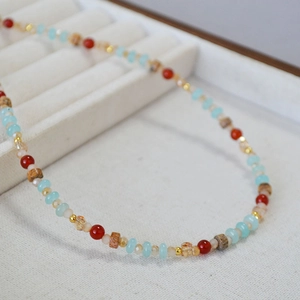 Détail d'un collier bohème avec perles colorées rouges, bleues et pierres texturées