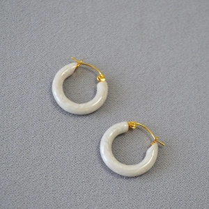 Retro white marble resin hoop earrings with gold metal clasp on grey fabric background