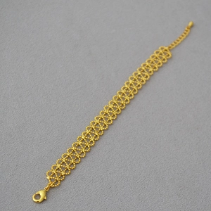Detailed macro view of vintage gold lace bracelet with mesh texture and lobster clasp