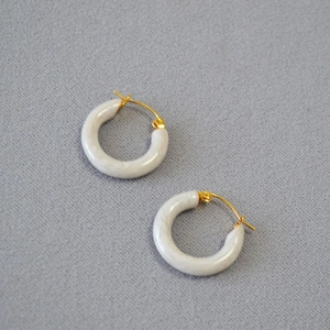 Detailed view of cream marble resin C-hoop earrings with elegant gold metal clasps