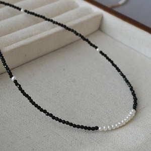 Detail of faceted black beads and white freshwater pearl necklace on a velvet display