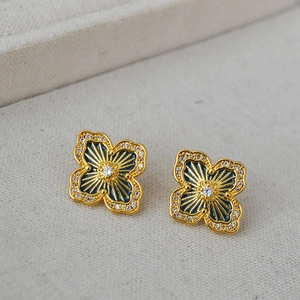 Detailed close-up of clover earrings with blue enamel and sparkling crystal accents