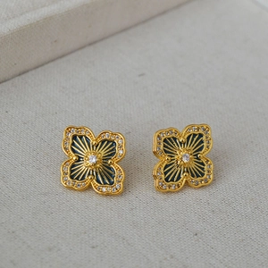 Detailed macro view of four-leaf clover earrings with blue enamel and gold sunburst texture