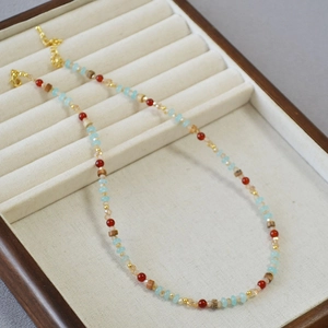Détail d'un collier de perles bohème avec perles bleues et rouges sur un plateau